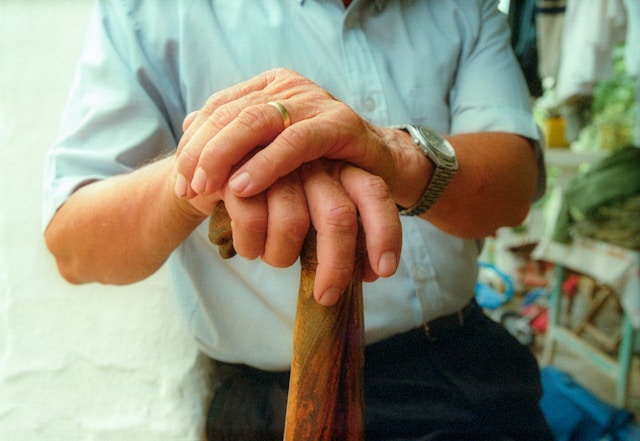 Man crossing hands on his walking stick